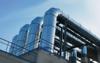 Sistema de ductos metálicos industriales para ventilación y extracción de aire en edificio industrial.